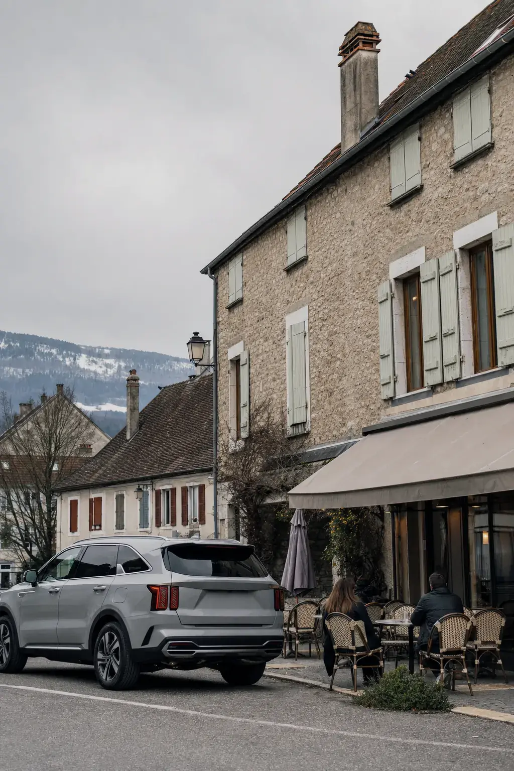 Rue du centre de Ferney-Voltaire, façades à volets et terrasse de café, le véhicule garé le long du trottoir